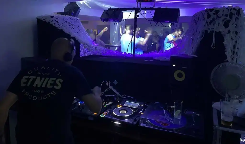 View of dj from behind the decks under UV light