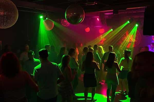 Crowd of people dancing at a disco with green and pink lighting